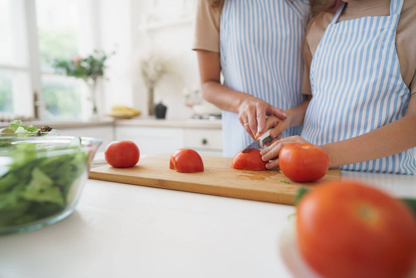 Close up of a woman and girl cutting vegetables for salad in kitchen - Foto, Bild