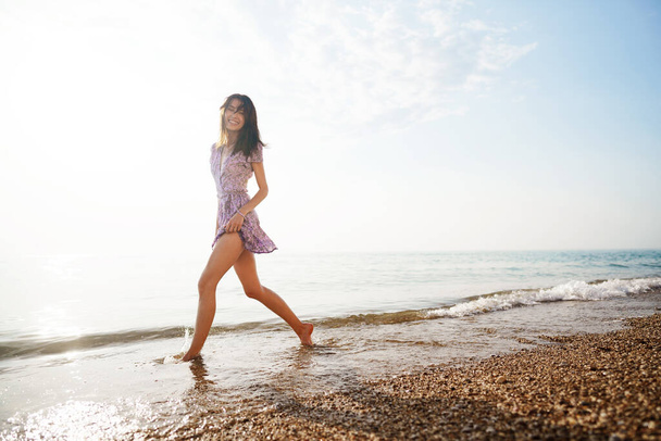 Portrait of young woman walking on the beach on sunrise - Foto, afbeelding