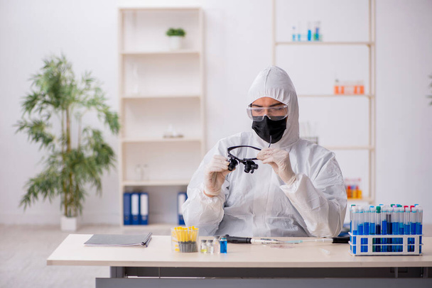 Jonge mannelijke chemicus werkt in het lab tijdens een pandemie - Foto, afbeelding