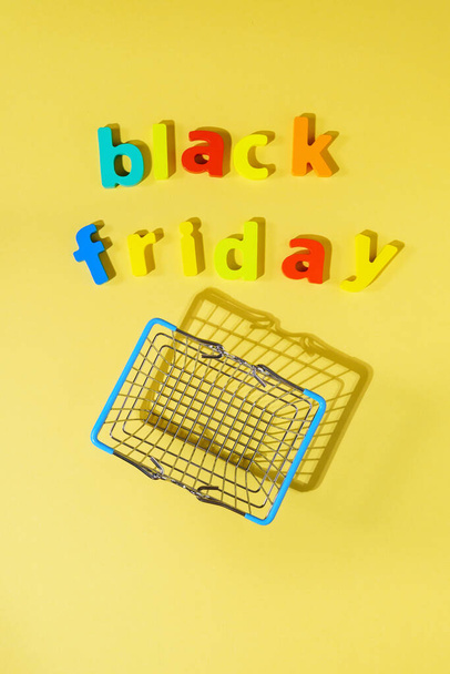 The inscription black Friday on a yellow background top view. Concept of sale discounts. Vertical photo - Zdjęcie, obraz
