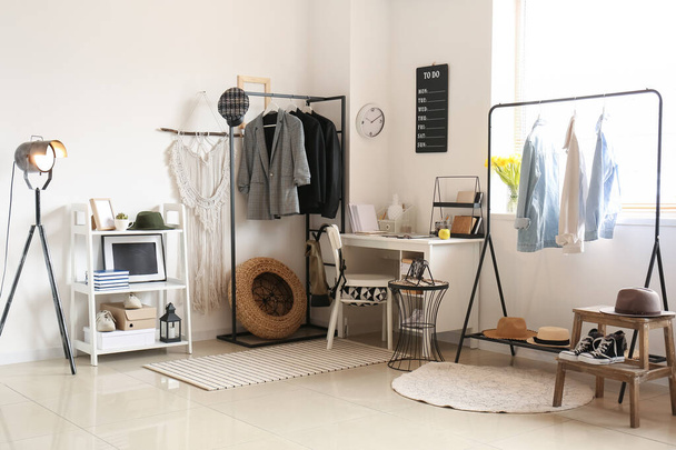 Interior de la habitación con lugar de trabajo moderno y ropa femenina con estilo - Foto, Imagen