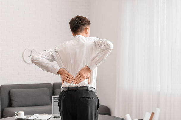 Young man suffering from back pain in office - Photo, Image