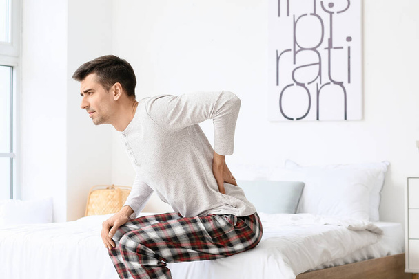 Nuori mies kärsii selkäkipu makuuhuoneessa - Valokuva, kuva