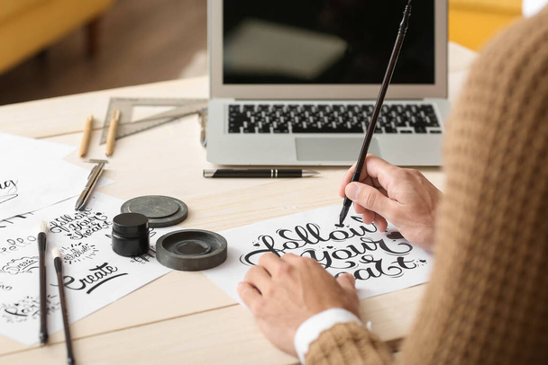 Fiatal férfi kalligráfus dolgozik az irodában, közelkép - Fotó, kép