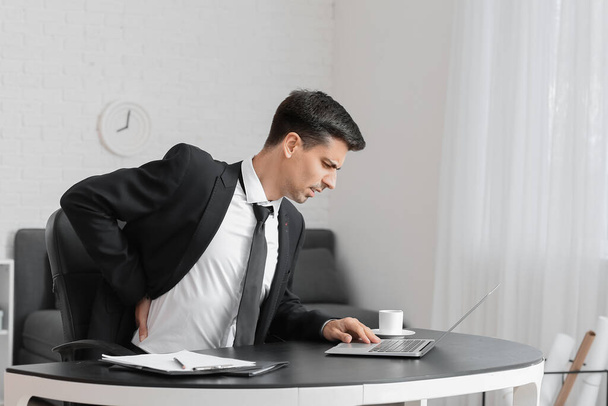 Молодой человек страдает от болей в спине в офисе - Фото, изображение
