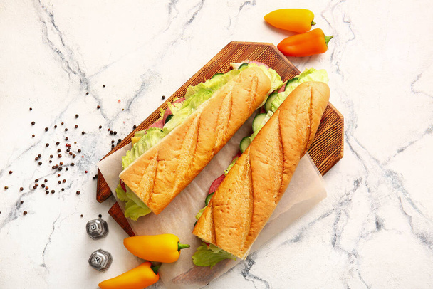 Tablero con sabrosos sándwiches sobre fondo claro - Foto, imagen