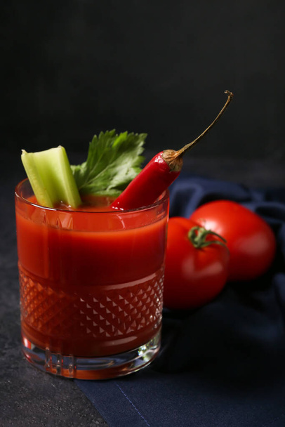 Glas Bloody Mary cocktail versierd met rode chili peper en tomaten op donkere achtergrond - Foto, afbeelding