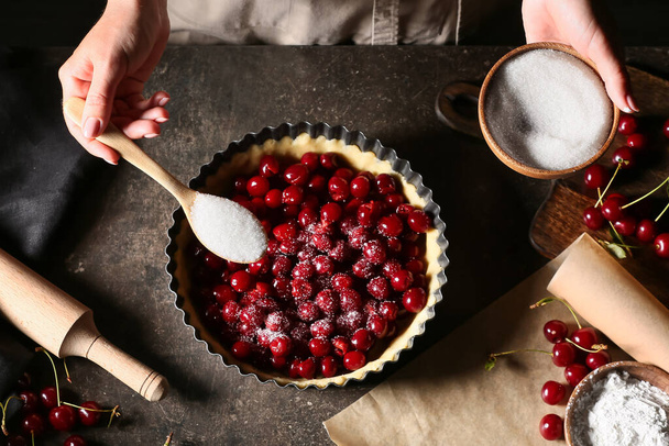 Woman cooking cherry pie at table - Photo, Image