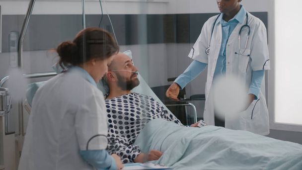Paciente discutiendo con los médicos mientras está acostado en la cama durante la recuperación de la enfermedad - Foto, imagen