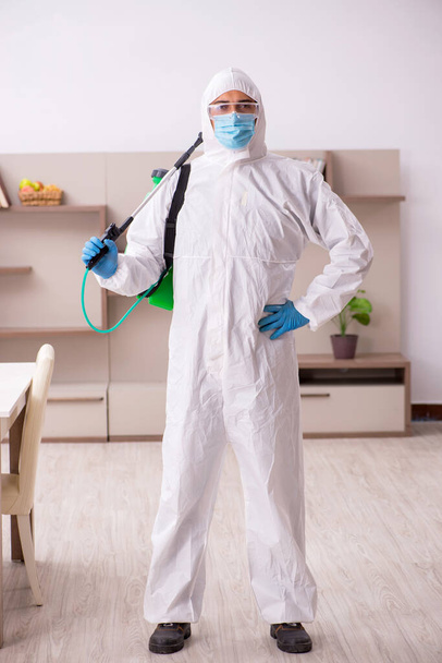 Contratista masculino joven desinfectando en casa - Foto, Imagen