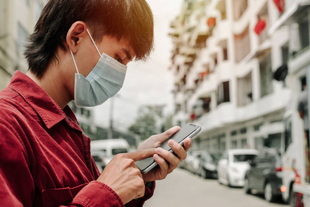 Człowiek w masce medycznej używa telefonu do szukania wiadomości. Koncepcja kwarantanny dla koronawirusów. MERS-Cov, nowy koronawirus (2019-nCoV) - Zdjęcie, obraz