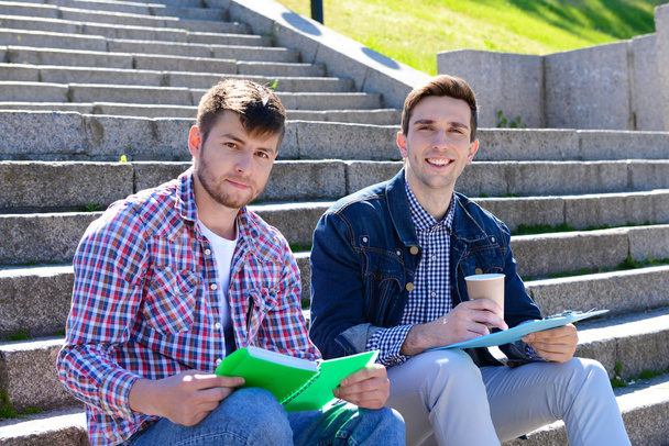 Students sitting on stairs in park - Foto, Bild