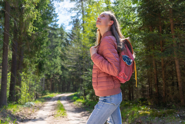 Pretty one teen young tourist girl relaxing on forests road.Teenage with backpack on green forest summer or spring.Closeup. - Valokuva, kuva