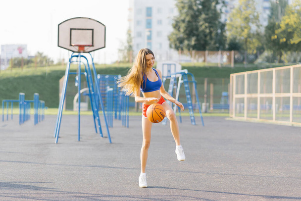 Γυναίκα παίζει μπάσκετ σε εξωτερικούς χώρους την ημέρα του καλοκαιριού. - Φωτογραφία, εικόνα