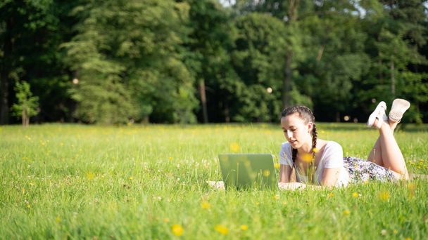 Üzleti ügy odakint. Diák lány dolgozik laptop, számítógép tabletta a nyári parkban. Online technológia női kültéri. Megszökött az irodai távoktatás koncepciójából - Fotó, kép