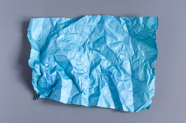 Crumpled green paper on a blue background. The texture of the crumpled paper for the background. - Zdjęcie, obraz