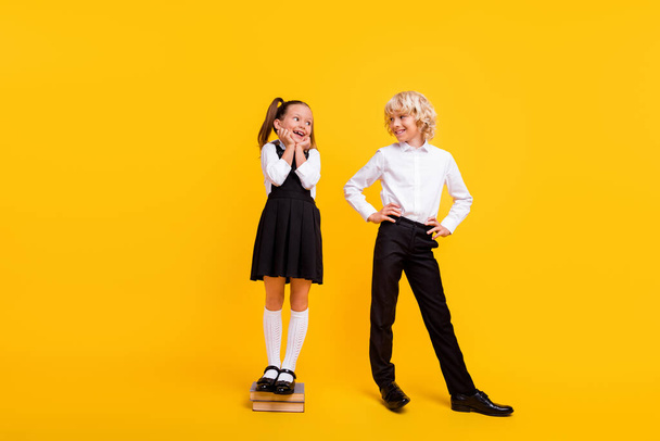 Photo of excited glad schoolchildren girl stay pile book wear school uniform isolated yellow color background - Φωτογραφία, εικόνα