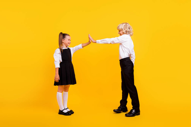Profile photo of funny playful kids clap hands give high five wear school uniform isolated yellow color background - Foto, imagen