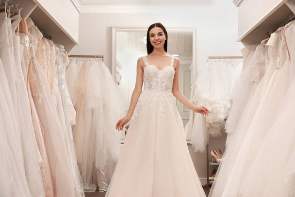 Woman trying on beautiful wedding dress in boutique - Fotoğraf, Görsel