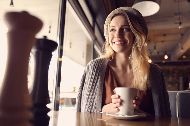 Молодая женщина с чашкой кофе в кафе утром - Фото, изображение