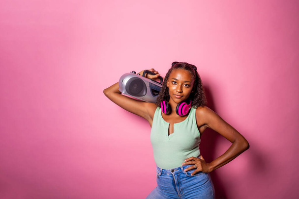 Junge schwarze Frau isoliert Musik hören hält Boombox aussehende Kamera zuversichtlich - Copyspace Werbebanner - Foto, Bild