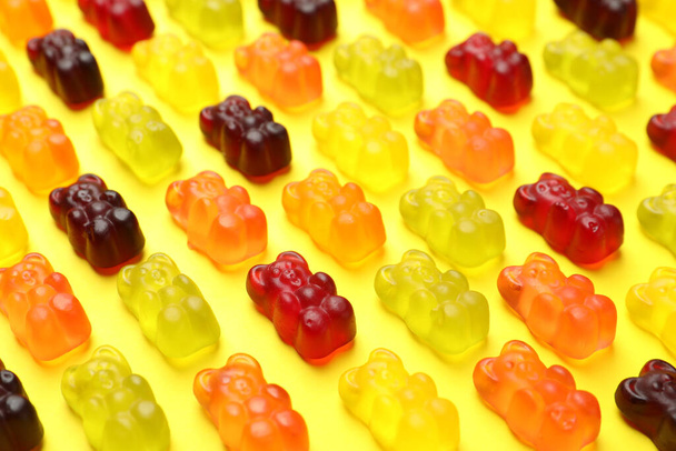 Delicious gummy bear candies on yellow background, closeup - Фото, изображение