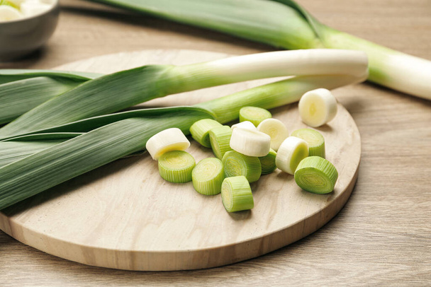Whole and cut fresh leeks on wooden table, closeup - 写真・画像