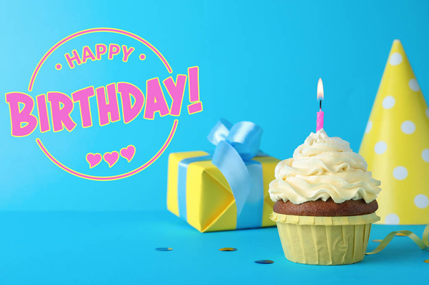 Happy Birthday! Delicious cupcake with burning candle on light blue background  - Фото, зображення
