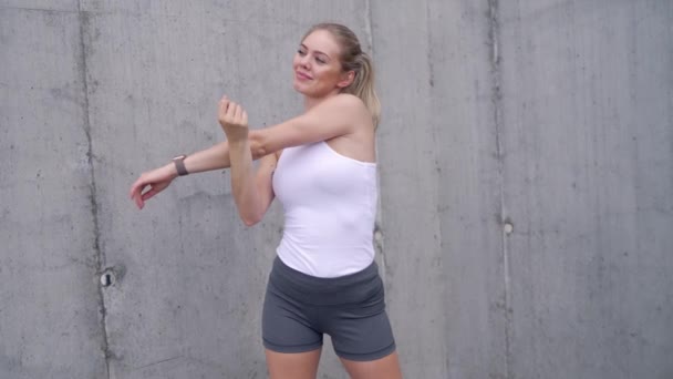 Glad sportswoman warming up on street - Footage, Video