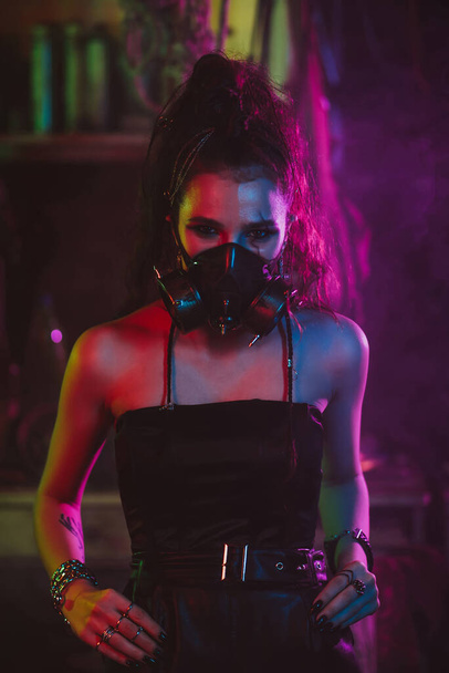 Cyberpunk cosplay. Dívka v plynové masce v post-apokalyptickém stylu s neonovým osvětlením - Fotografie, Obrázek