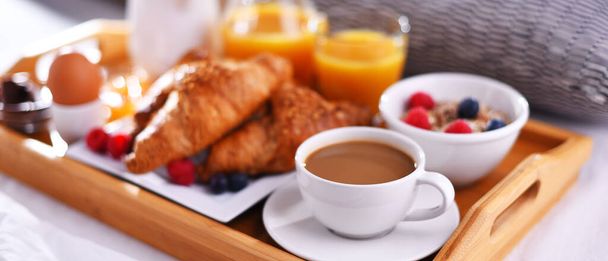 Tablett mit Frühstück auf dem Bett im Hotelzimmer. - Foto, Bild