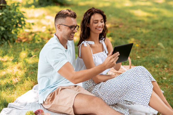 happy couple with tablet pc at picnic in park - Fotó, kép