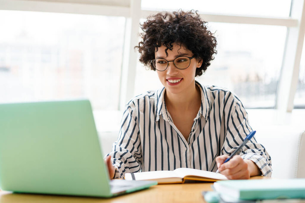 Mulher feliz bonita em óculos usando laptop enquanto trabalhava no café - Foto, Imagem