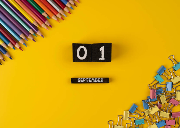 Calendario de madera con la fecha del 1 de septiembre sobre fondo amarillo. Cerca de los clips de papel y lápices. calendario de madera - Foto, imagen
