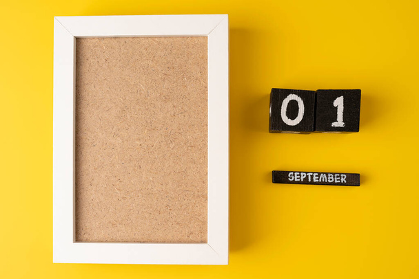 1 de setembro em um calendário de madeira em um fundo amarelo com moldura de foto branca vazia. Voltar ao conceito de escola - Foto, Imagem