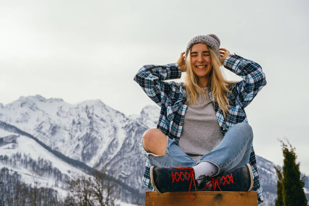 Beautiful young woman wearing knitted hat and casual clothes enjoying good weather in mountains. - Valokuva, kuva