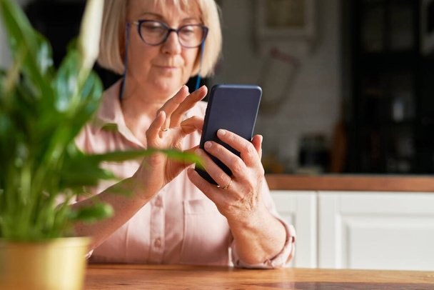 Close up of mature woman using mobile phone                                 - Foto, afbeelding