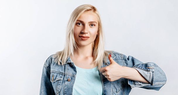 Smiling woman showing thumbs up and looking at the camera over white background. Positive girl shows like. OK - Fotografie, Obrázek