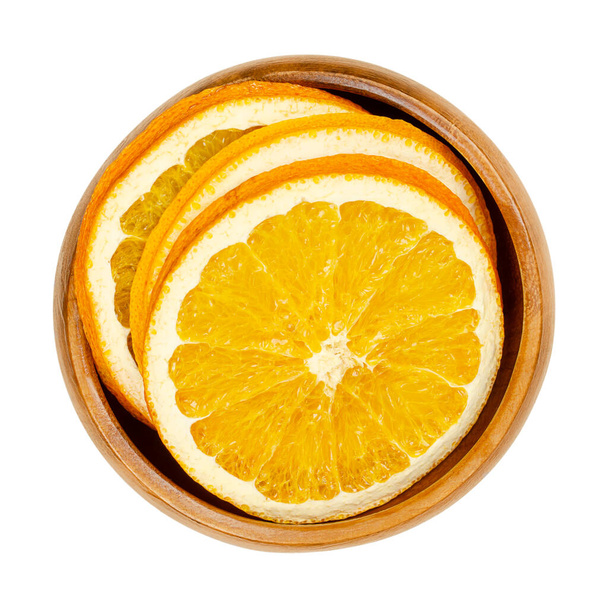 Kuivattuja appelsiininviipaleita puisessa kulhossa. Appelsiinit, leikataan poikkileikkauksiksi, viipaloidut hedelmät, joita käytetään aromaattisina tuoksuvina joulukoristeina. Lähikuva, ylhäältä, eristetty valkoisella taustalla, makrokuva. - Valokuva, kuva