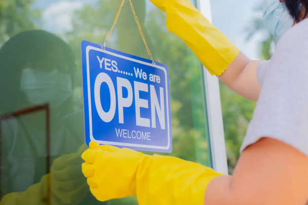 The owner of the store hangs a sign to open a business in front of the door. - 写真・画像