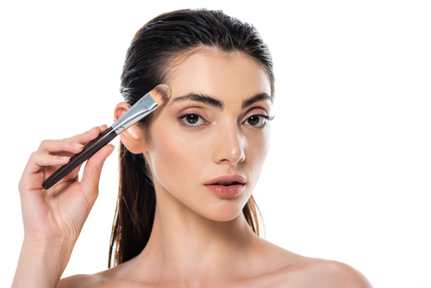 brunette woman applying face foundation with cosmetic brush isolated on white - Photo, Image