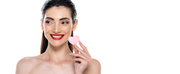 femme positive avec des lèvres rouges tenant éponge de beauté en forme de coeur isolé sur blanc, bannière - Photo, image