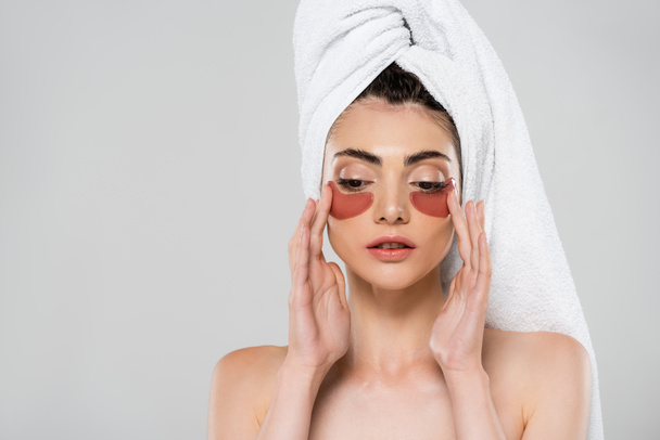 young woman with towel on head applying eye patches isolated on gray - Foto, Imagem