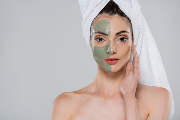 jeune femme aux épaules nues et masque d'argile verte sur le visage isolé sur gris - Photo, image
