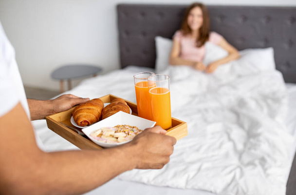 Romantic black guy bringing breakfast to bed for his beloved woman, closeup of hands - Foto, Imagen