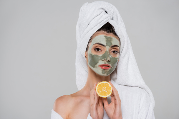 young woman with green clay mask holding orange half isolated on grey - 写真・画像