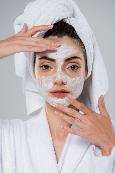 pretty woman with towel on head applying face scrub isolated on grey  - Foto, Bild