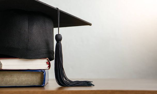 Bordo di malta con carta di laurea e libri su tavola di legno. concetto di graduazione. - Foto, immagini