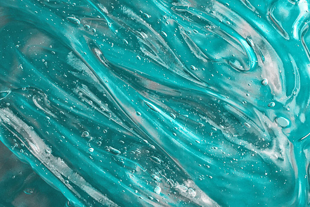 Suero ondulado de turquesa con burbujas en el fondo verde.Frotis cosmética de aloe vera o gel antibacteriano.Bueno como maqueta con espacio de copia.Anuncio. - Foto, Imagen