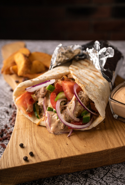 doner kebab, a shawarma in a pit of fresh vegetables and meat. with large spices. restaurant serving. on a dark background. for menus and ads - Foto, Imagem